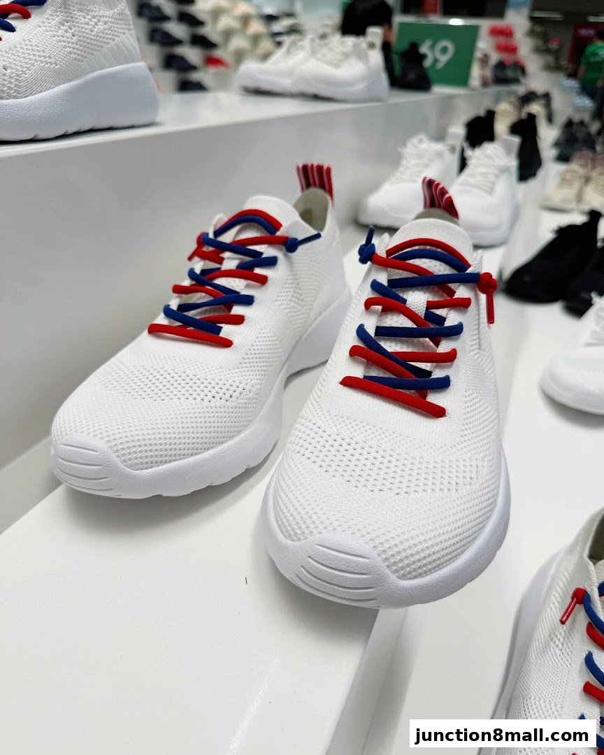 Close-up view of white sneakers with red and blue laces displayed on a shelf.