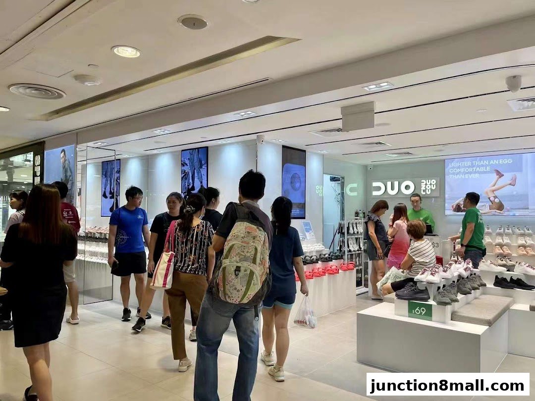 Customers browse shoes inside a brightly lit DUOZOULU store with displays of footwear and promotional screens.