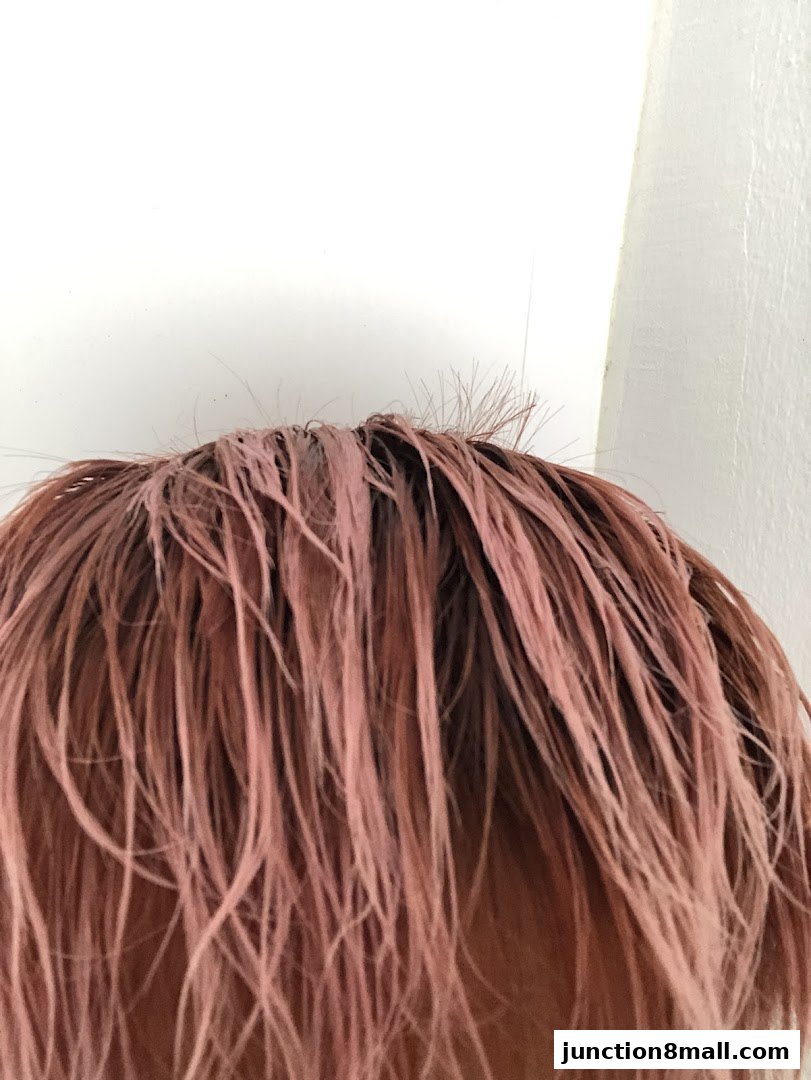 Close-up of a person's hair with a pinkish-brown hue, styled in a messy manner.