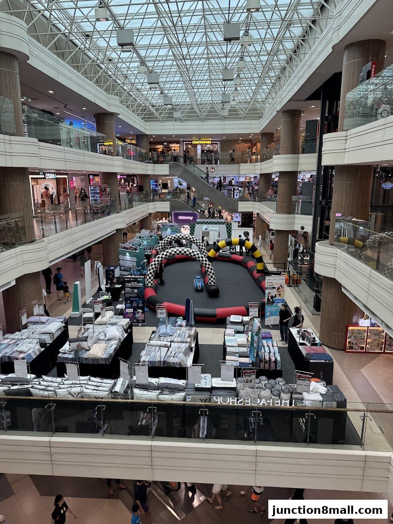 A busy shopping mall atrium with a go-kart track and retail displays.
