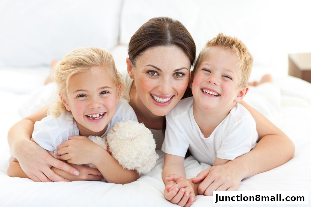 A mother and her two children are smiling and lying on a white surface.