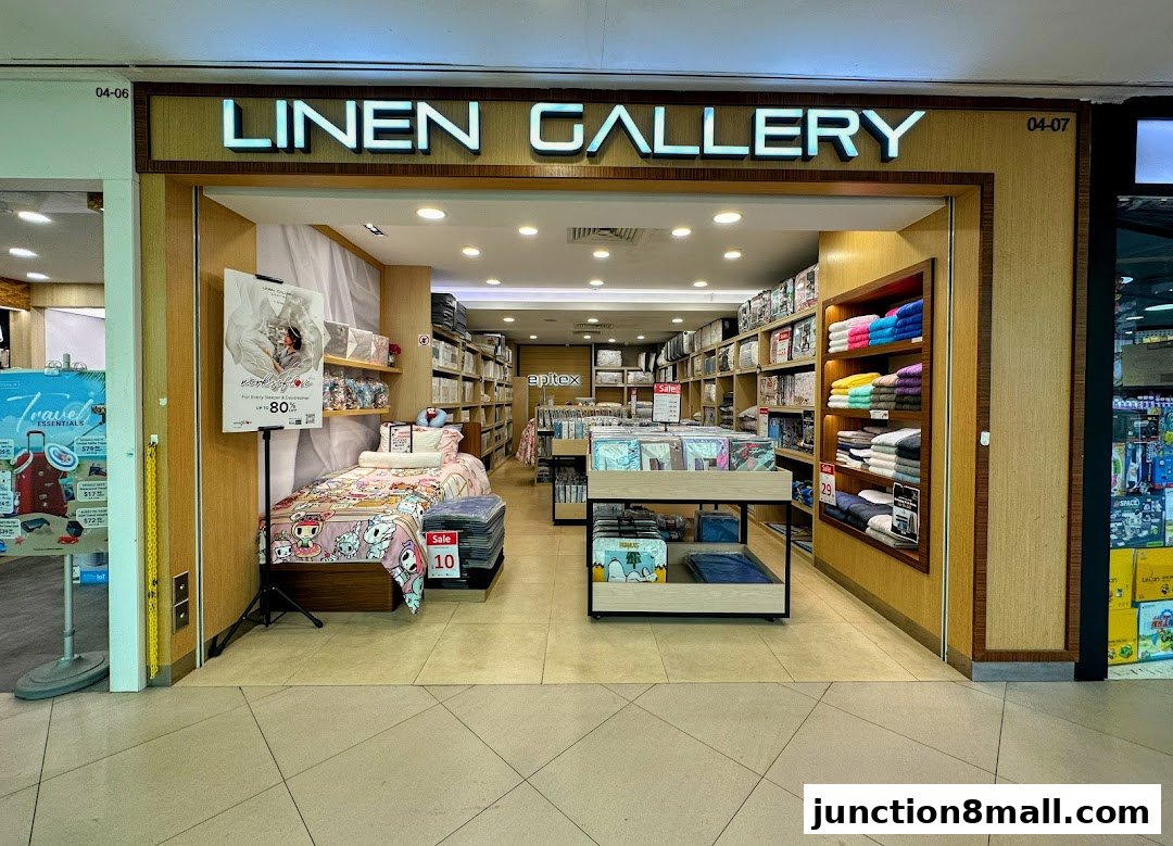 The entrance of a bedding and linen store, showcasing beds, shelves of folded towels, and bedding sets.