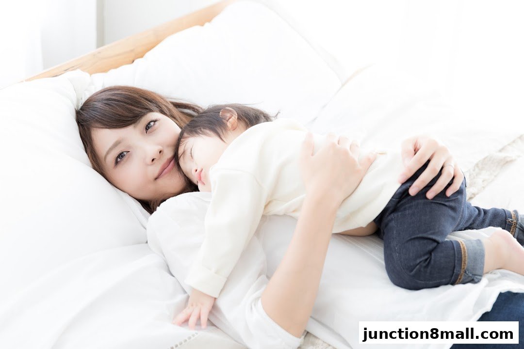 A mother lovingly holds her sleeping baby on a bed.
