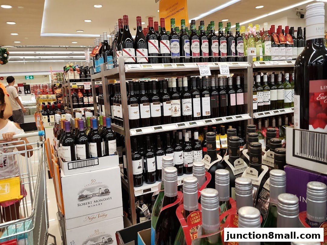 A wide selection of wine bottles displayed on shelves in a well-lit supermarket aisle.