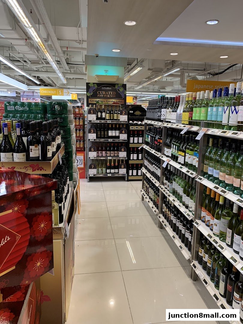 Aisle in a supermarket with shelves stocked with wine bottles and other beverages.