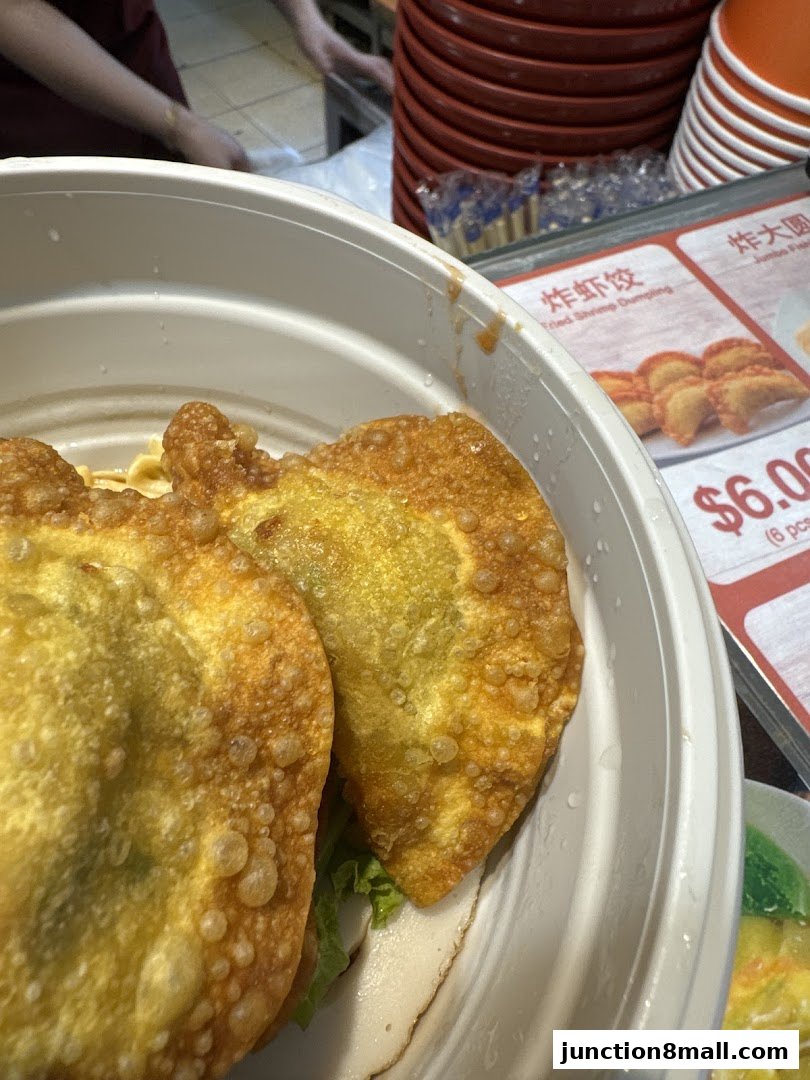 Close-up of crispy fried wontons served in a bowl with a menu in the background.