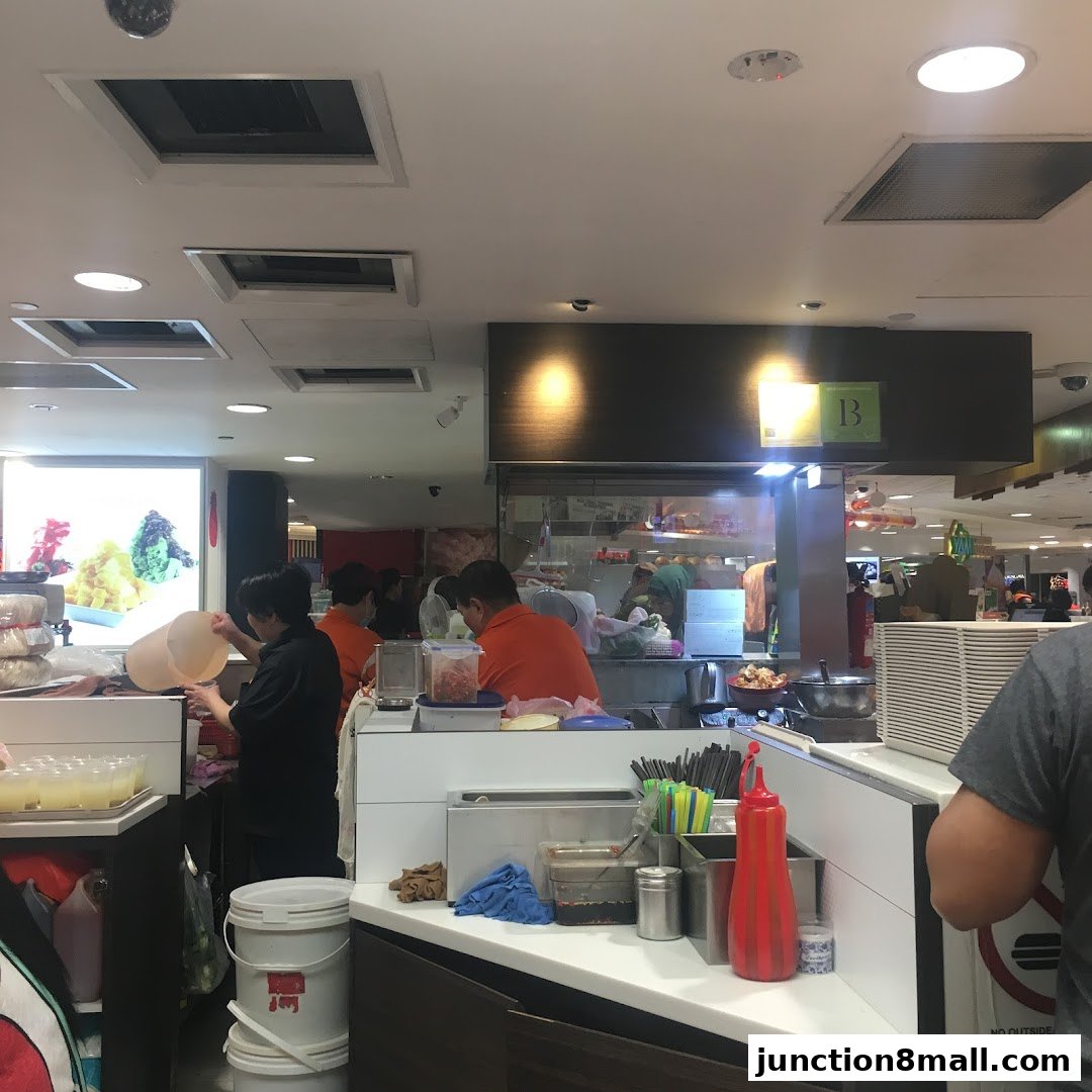 Staff working behind the counter at a food stall, preparing orders.