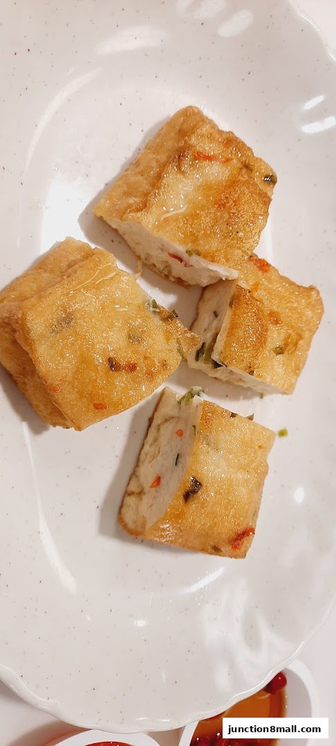 Golden fried tofu cubes with visible chili and scallion pieces served on a white plate.