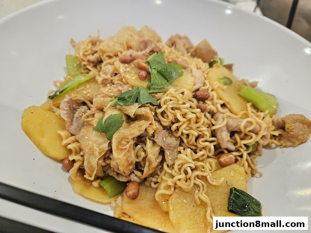A close-up shot of a delicious noodle dish with meat, potatoes, and vegetables.