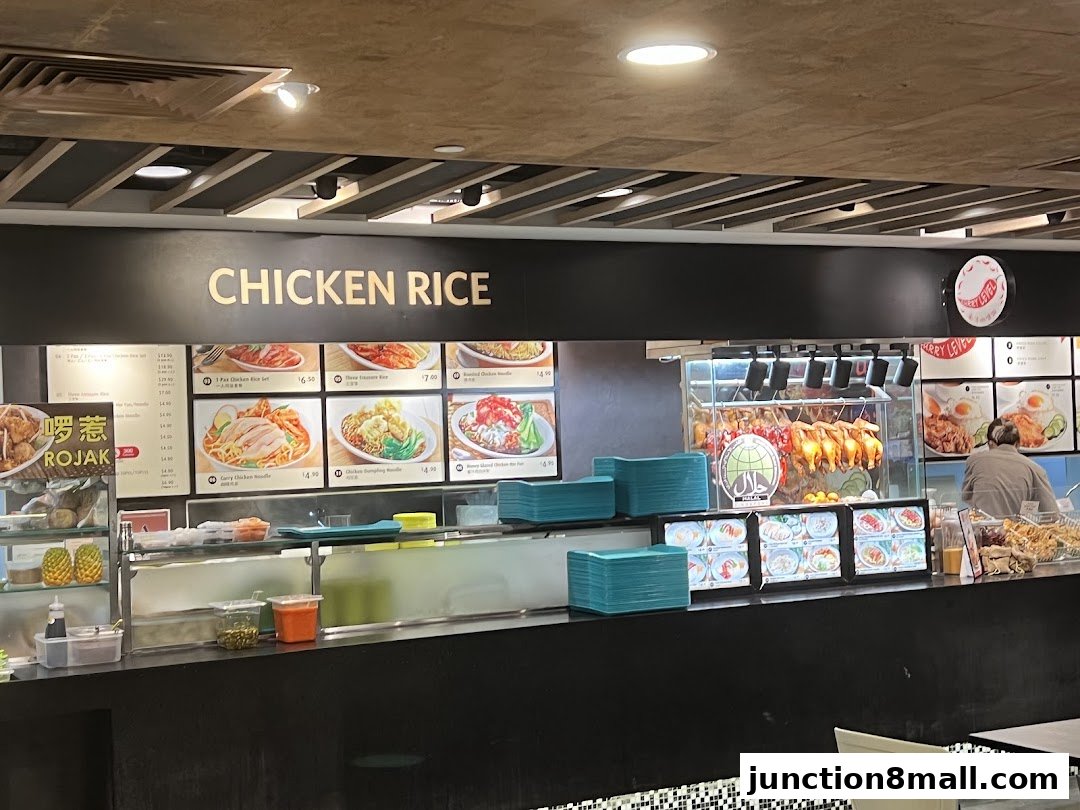 A food stall counter with a prominent 'CHICKEN RICE' sign and displayed food items.