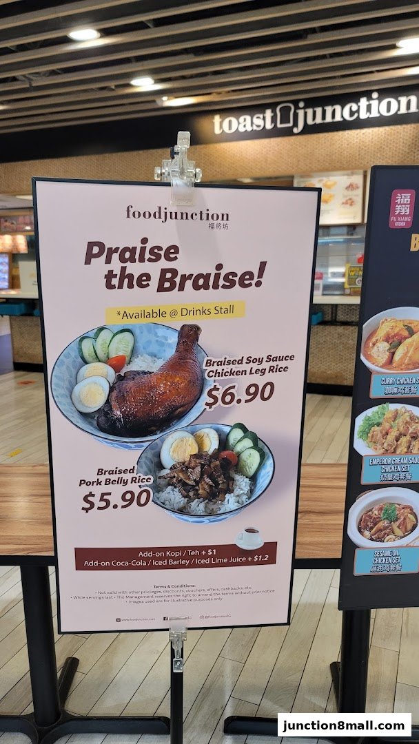 A promotional sign for Food Junction featuring braised rice dishes and drinks.