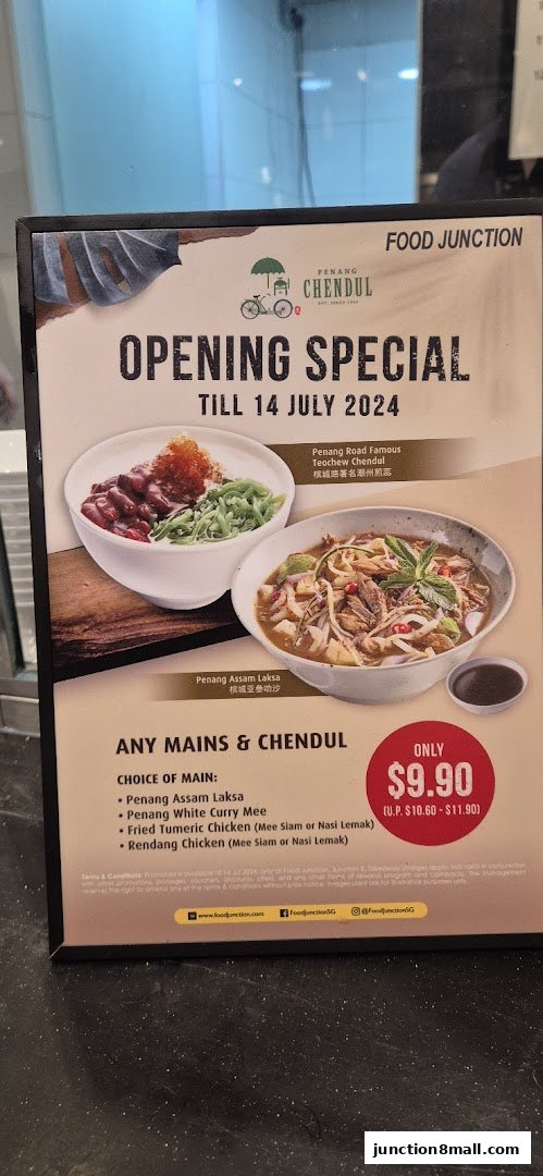 A promotional sign for Food Junction's opening special featuring Penang Assam Laksa and Chendul.