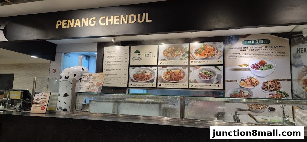A food stall counter displaying a menu with various Malaysian dishes and prices.