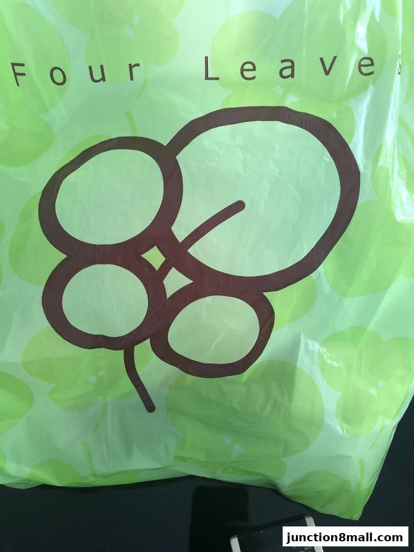 A light green shopping bag with the "Four Leaves" logo and a clover pattern.