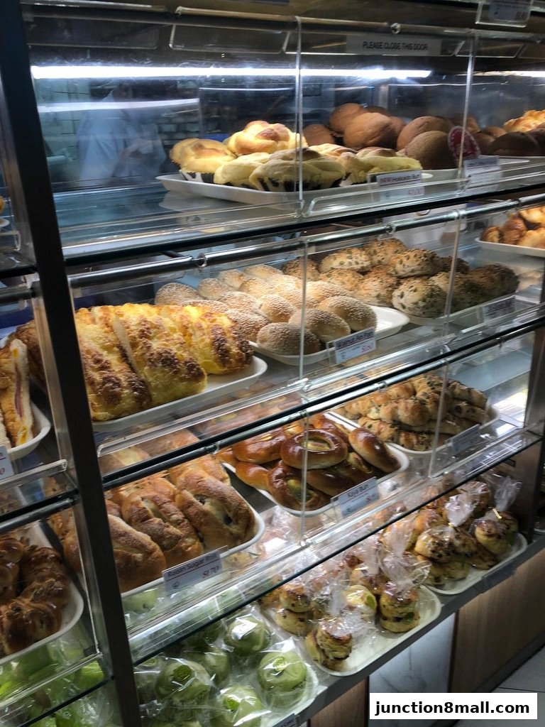 A display case filled with various freshly baked breads, buns, and pastries.