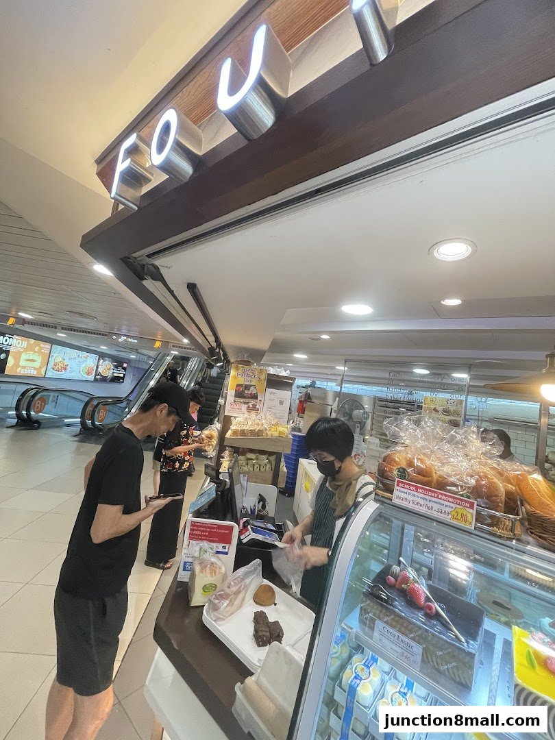 Customers are served at a bakery counter with a display of pastries and bread.
