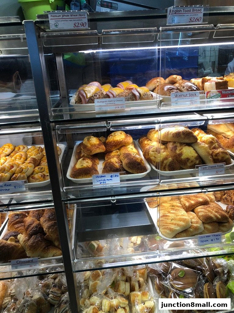 A display case filled with various baked goods including bread, pastries, and sandwiches.