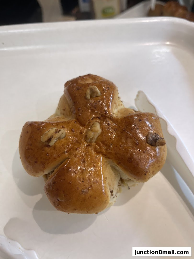 A close-up of a golden-brown, star-shaped pastry with walnuts on a white tray.