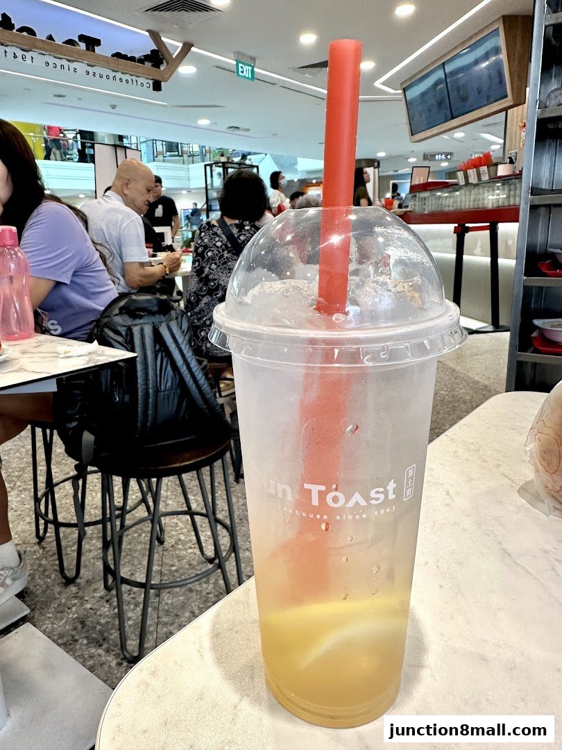 A close-up of a refreshing drink with a red straw at Fun Toast, with people dining in the background.