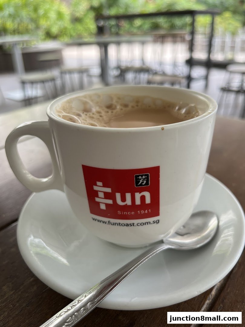 A close-up of a cup of coffee with foam, branded with the Fun Toast logo.