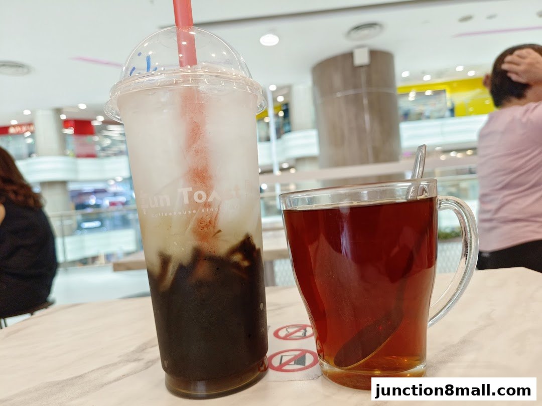 Two drinks, a tall iced beverage and a mug of tea, sit on a table at Fun Toast.