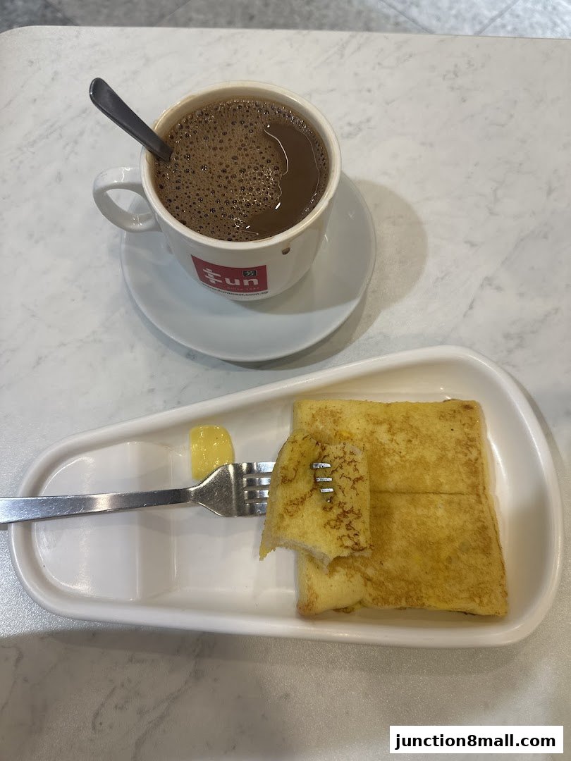 A cup of coffee and French toast with butter on a white plate.