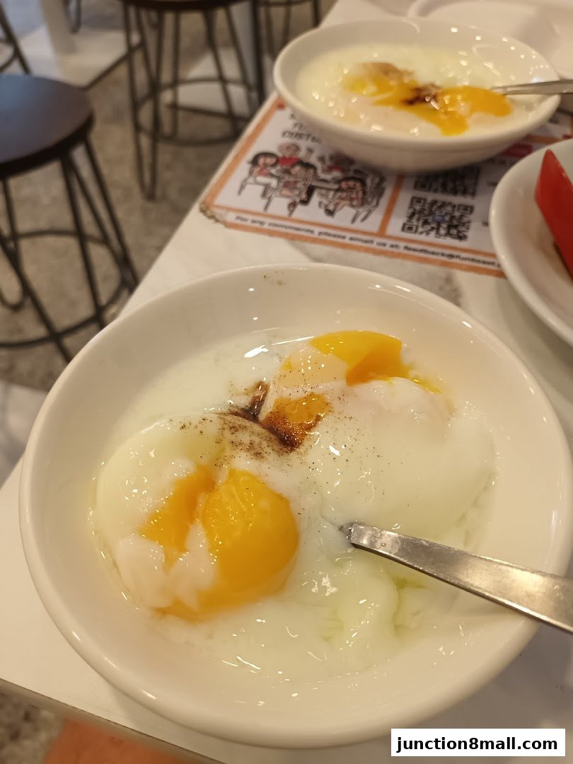 Two bowls of soft-boiled eggs with soy sauce and pepper, served with a spoon.
