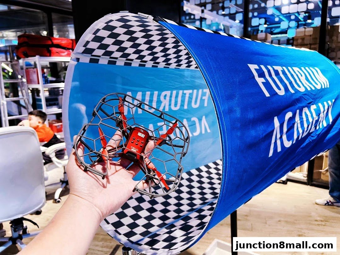A hand holds a small drone inside a tunnel with the Futurum Academy logo.