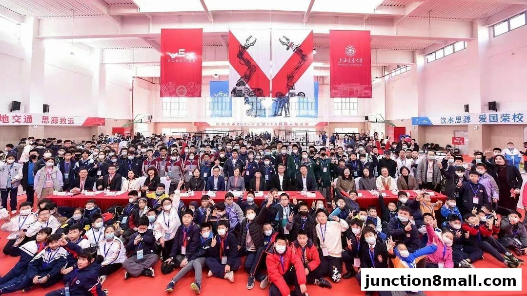 A large group of students and adults pose for a photo at an event, with VEX Robotics banners overhead.