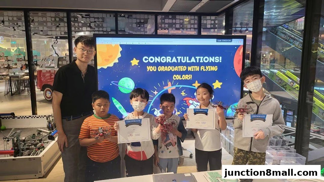 Students and instructor celebrate graduation with certificates and robotic projects.