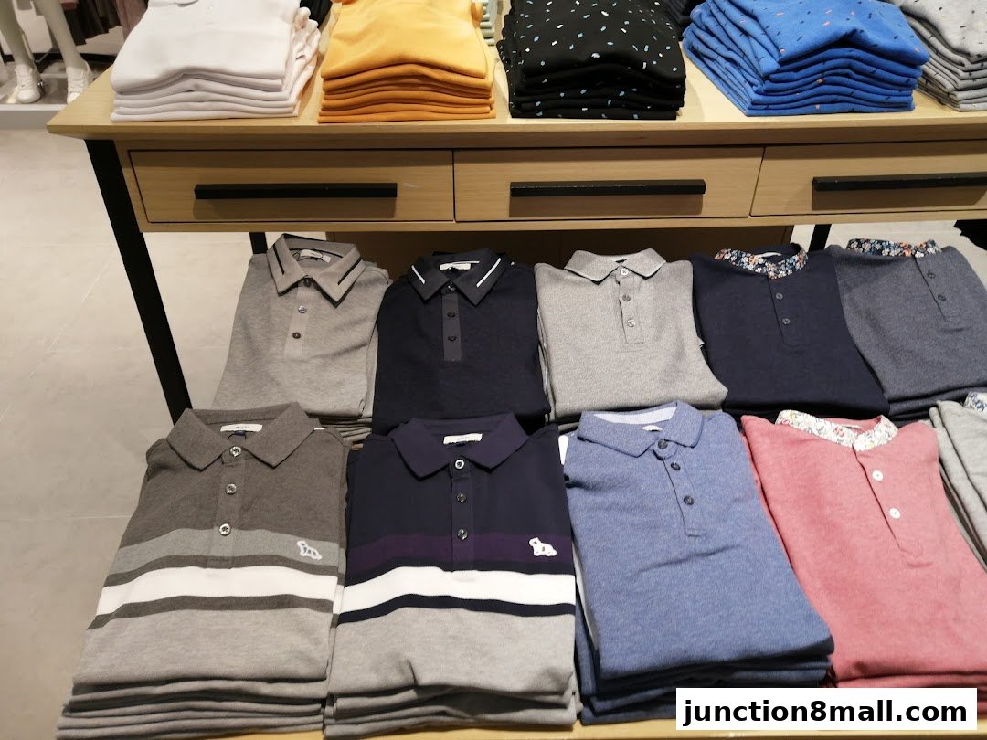 Neatly folded polo shirts in various colors and patterns displayed on shelves.