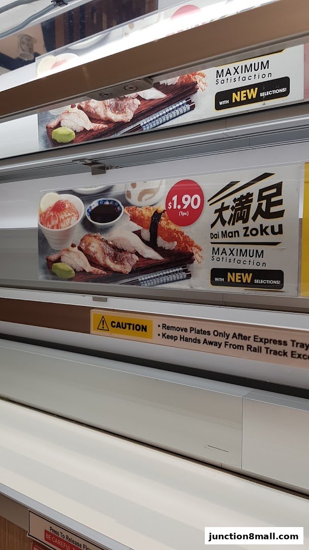 A conveyor belt sushi restaurant display featuring various sushi dishes and promotional text.