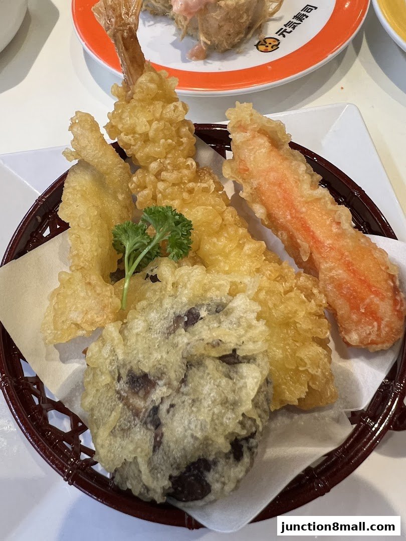 A basket of assorted tempura items, including shrimp and vegetables, served at a sushi restaurant.