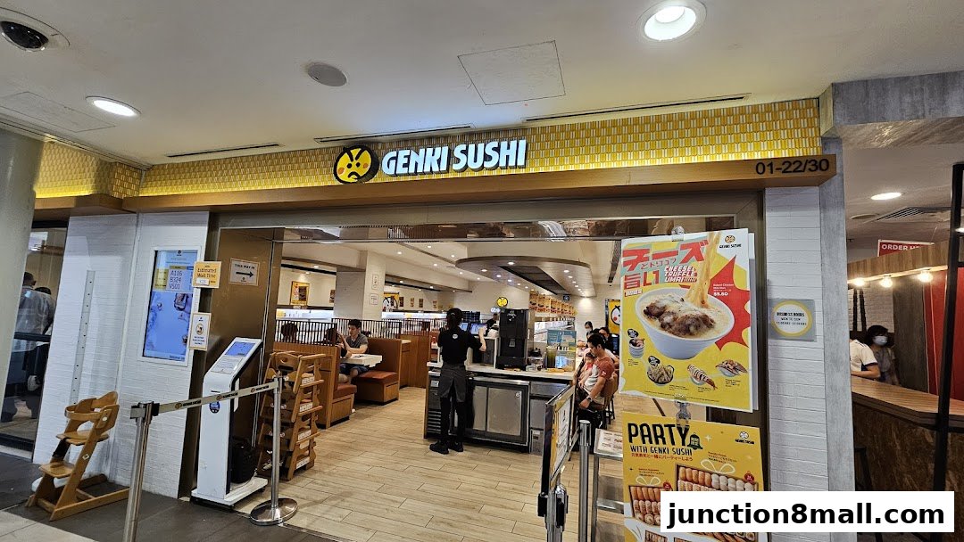 The entrance of Genki Sushi Junction 8, showing the storefront, seating area, and promotional posters.