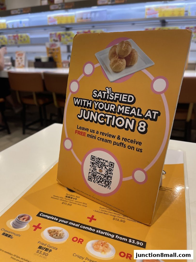 A sign offering free cream puffs for reviews at Genki Sushi Junction 8.