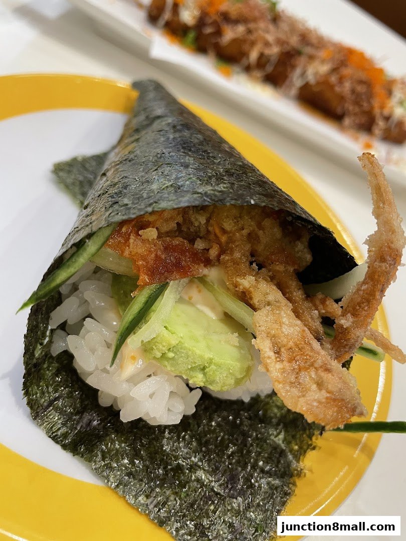A close-up of a delicious soft shell crab sushi hand roll on a yellow plate.