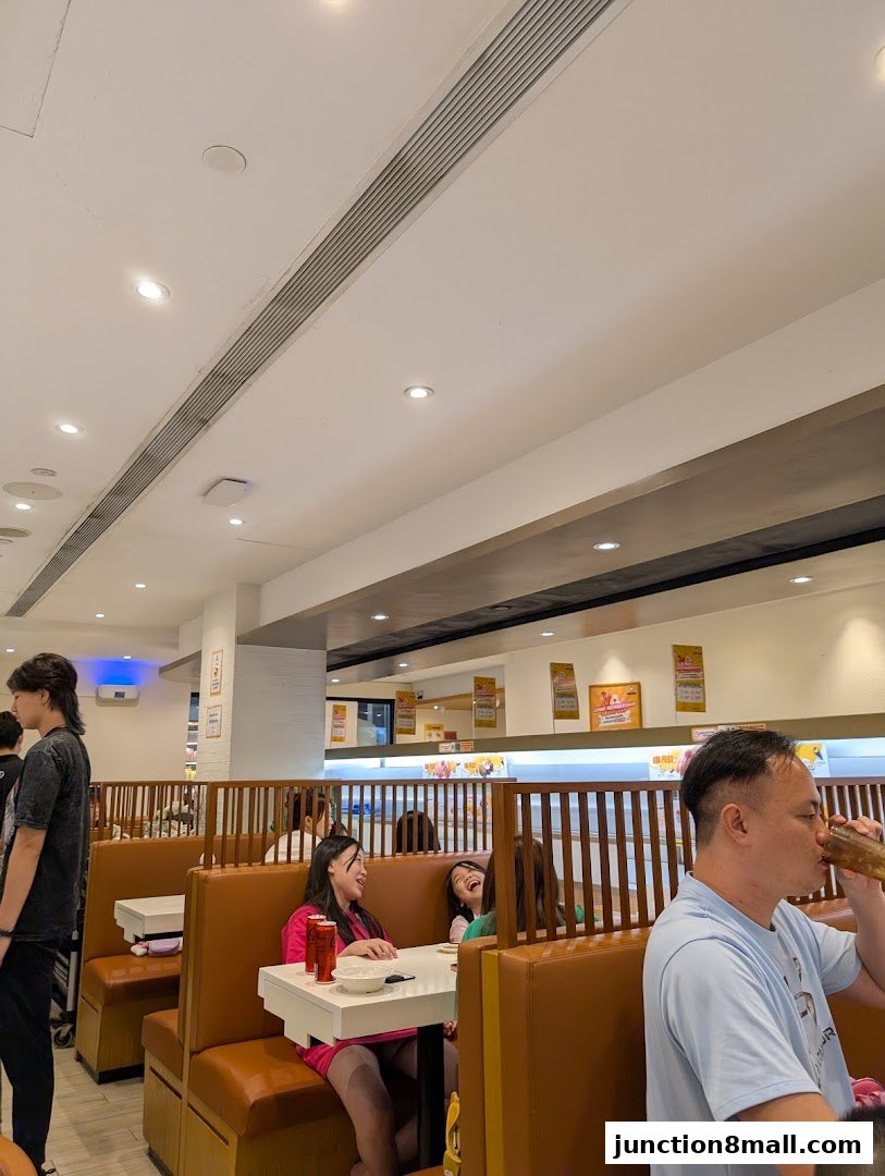 Diners enjoying a meal in a brightly lit sushi restaurant with booth seating.