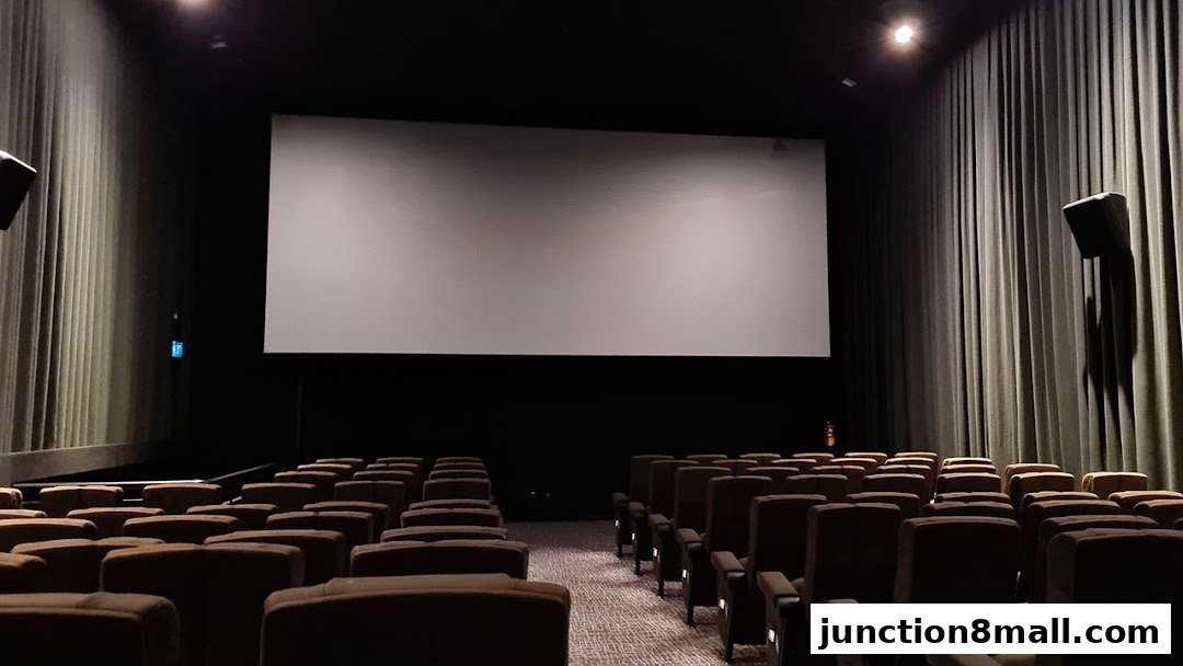An empty cinema hall with rows of plush seats facing a large screen.