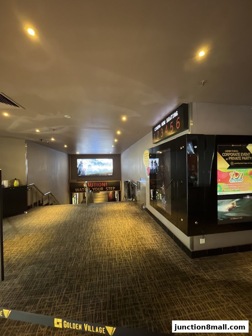 Interior view of a cinema lobby with a digital display showing seating and movie posters.