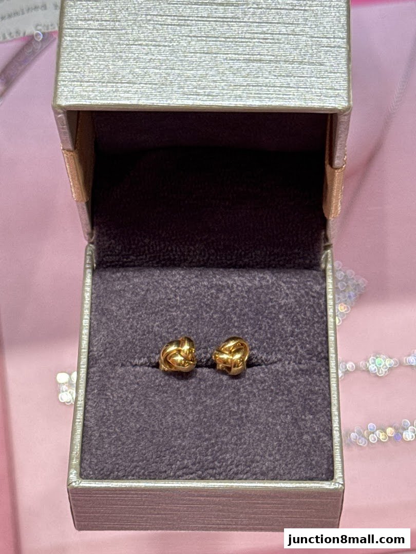 A pair of gold knot earrings displayed in an open jewelry box.