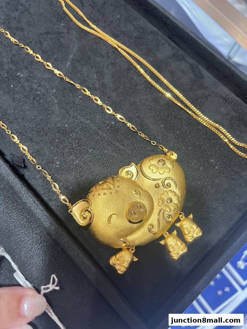 A close-up of a gold pig pendant necklace with three smaller pig charms.