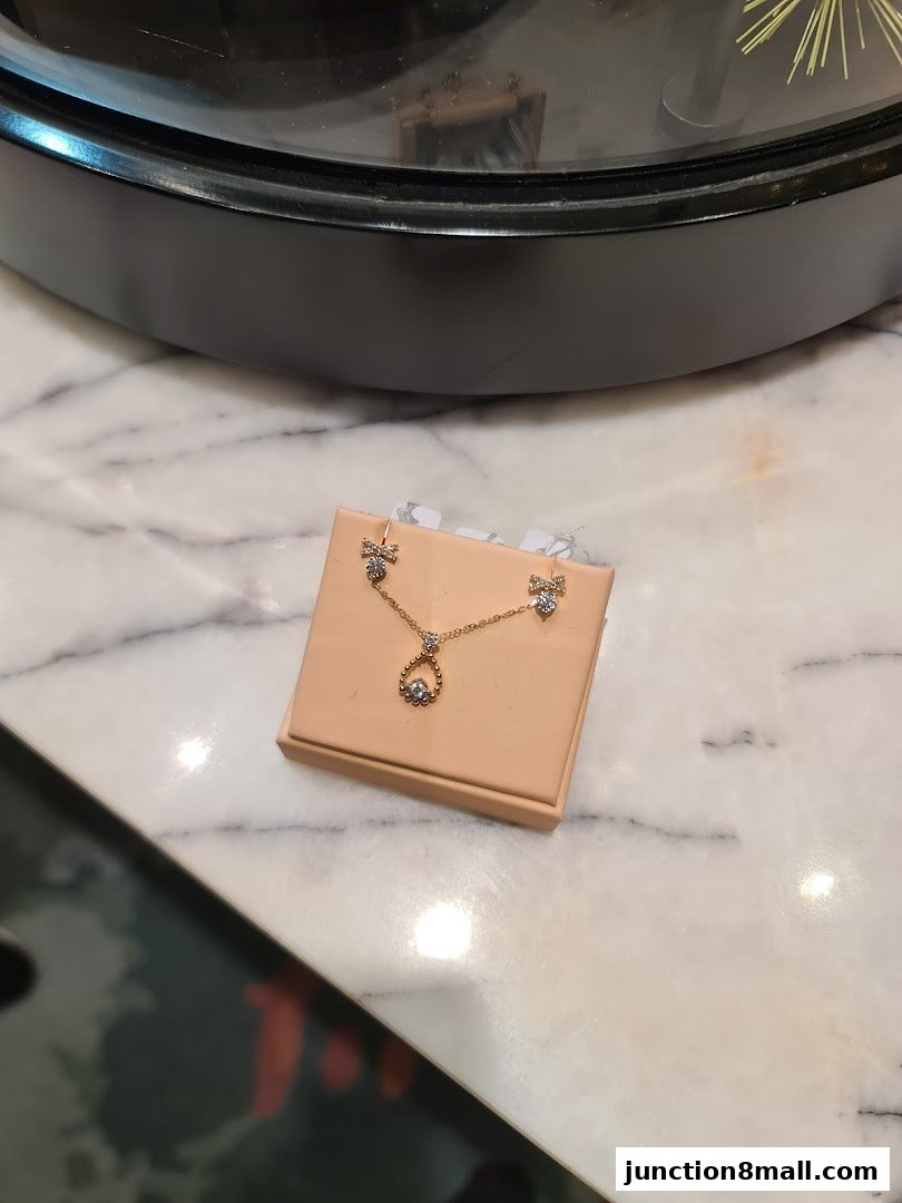 A delicate gold necklace and earrings set with small diamonds on a display stand.