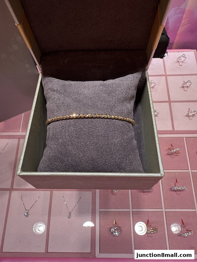 A gold and silver twisted bracelet displayed in an open jewelry box.