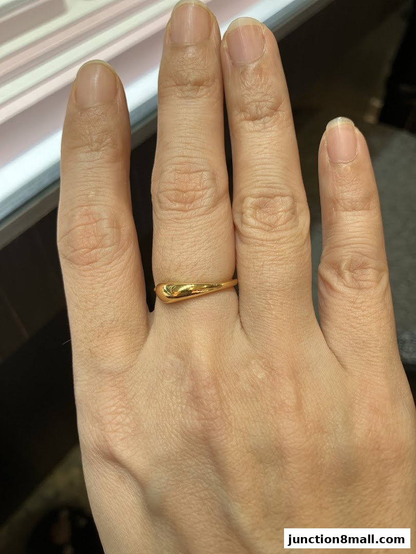 A hand wearing a simple gold ring with a smooth, teardrop-shaped design.