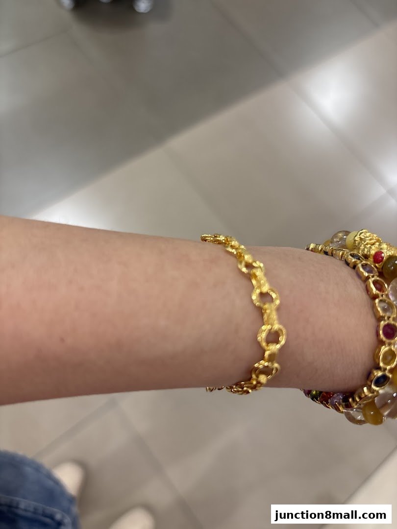 A close-up shot of a person's arm wearing two gold bracelets, one with a chain link design.