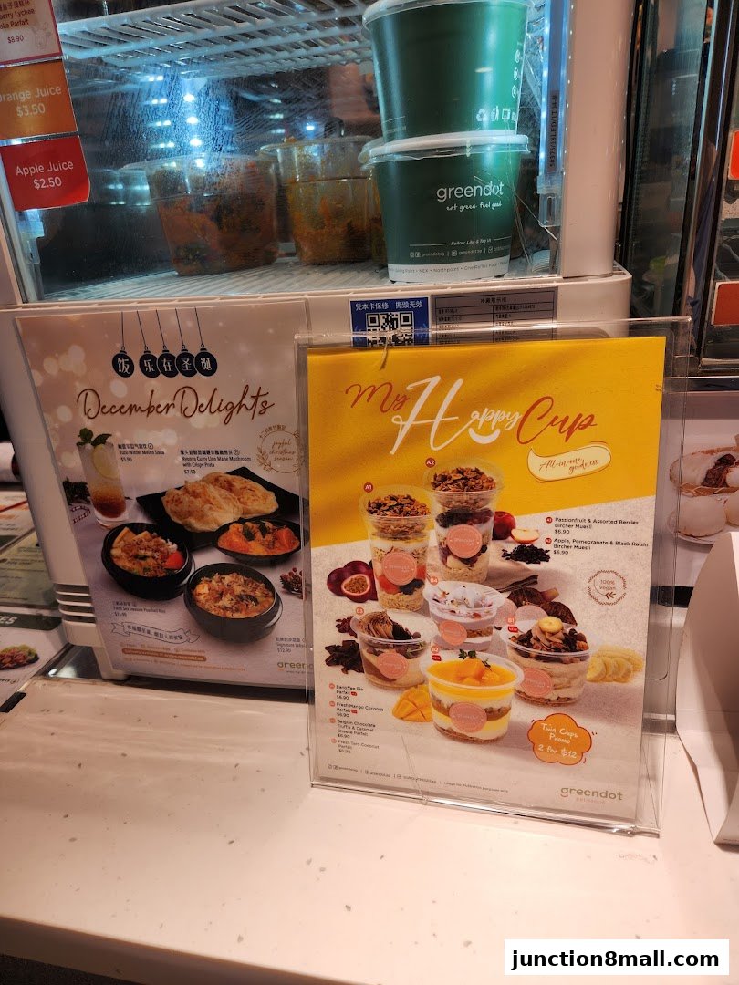 A display of food and drink items from Greendot, featuring a December Delights menu and 'My Happy Cup' promotion.