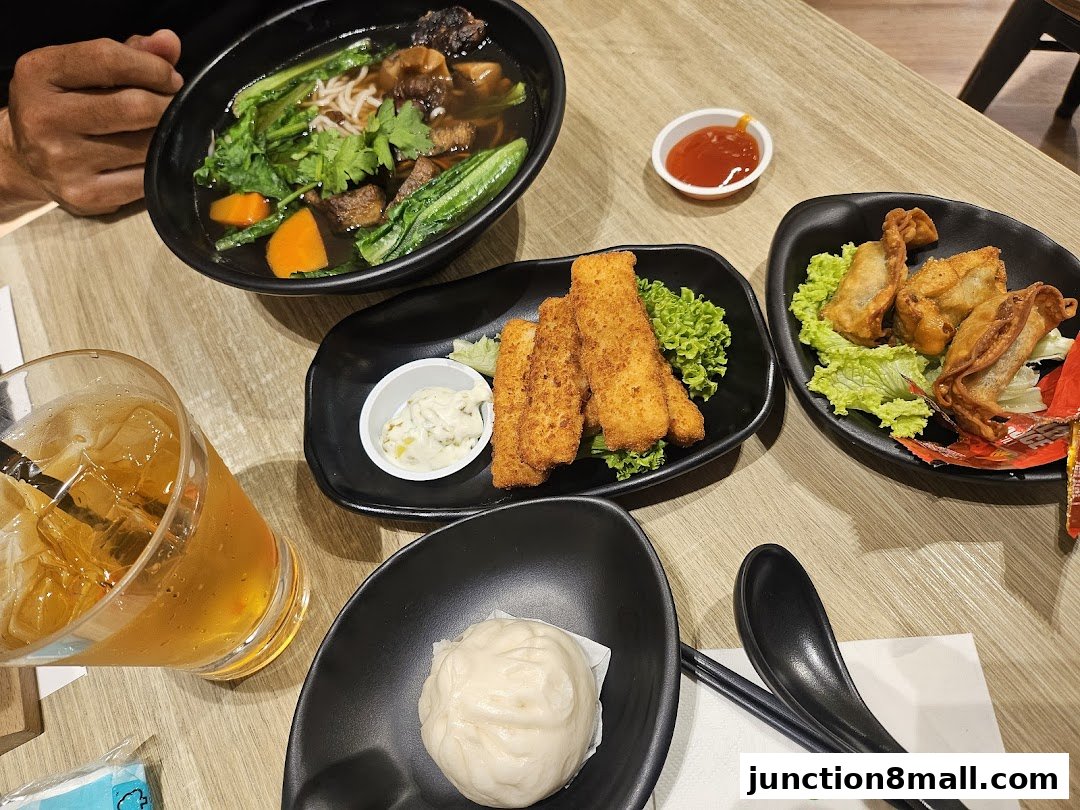 A table laden with various dishes including noodles, fried items, dumplings, and a drink.