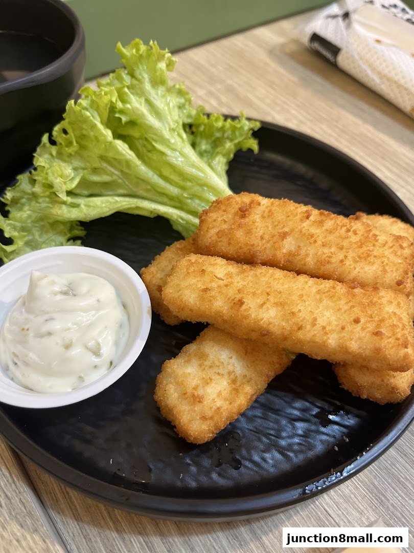 A plate of golden-brown fish fingers with a side of tartar sauce and lettuce.