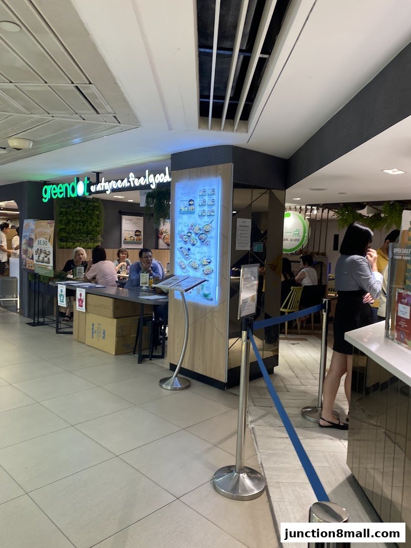 A Greendot restaurant interior with customers dining and a menu display.