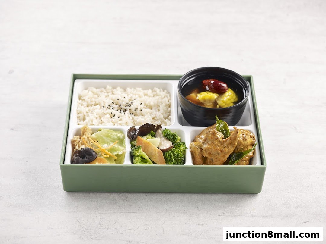 A bento box with rice, soup, vegetables, and chicken.